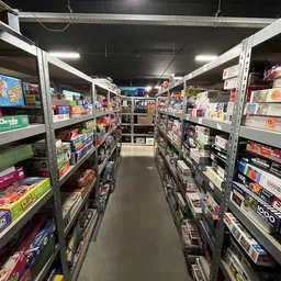 Winkelgang met metalen stellingen vol dozen en verpakkte goederen aan beide zijden