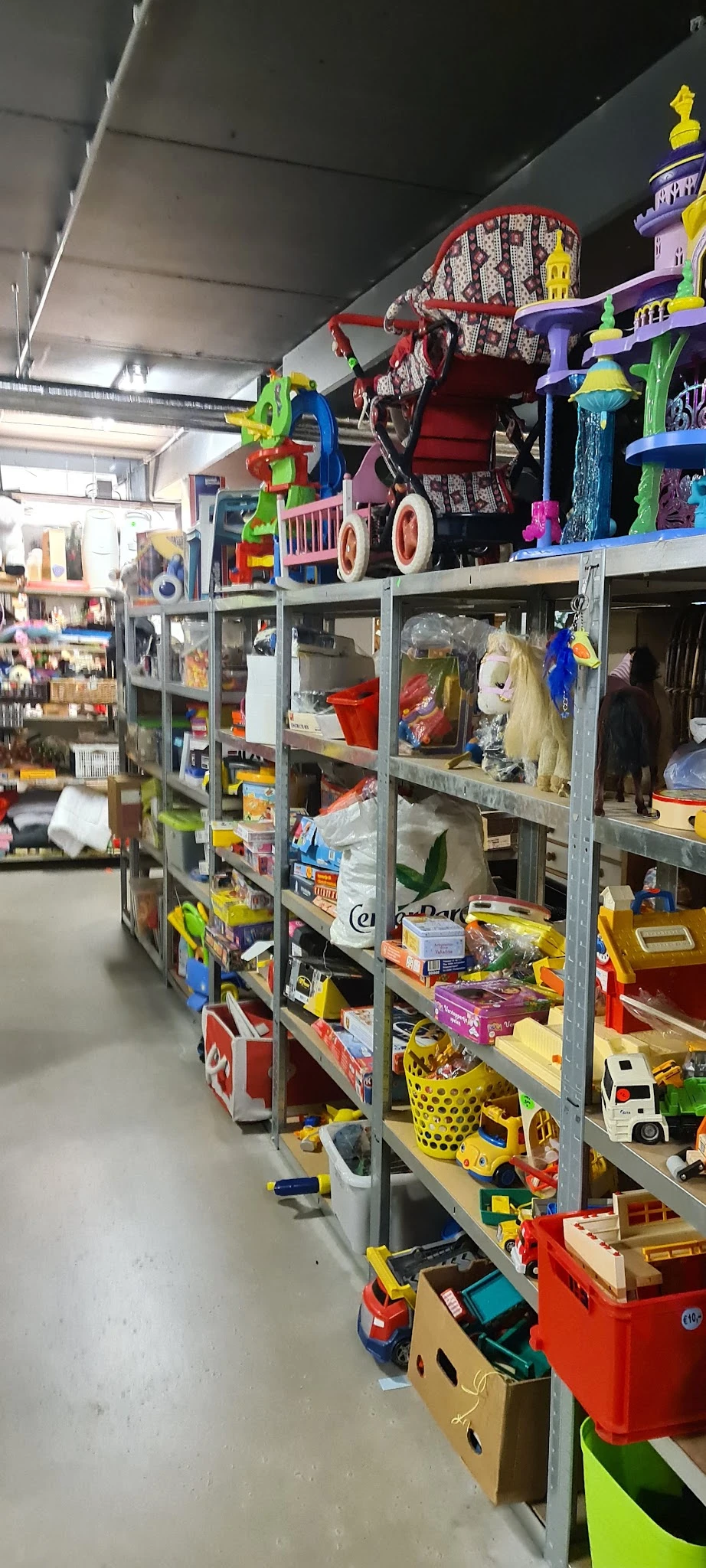 Metalen stellingen vol met diverse tweedehands artikelen zoals speelgoed, huishoudartikelen en kleding