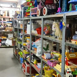 Metalen stellingen vol met diverse tweedehands artikelen zoals speelgoed, huishoudartikelen en kleding