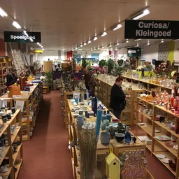 Winkelvloer met houten stellingen vol spullen, twee secties met bordjes 'Speelgoed' en 'Curiosa/Kleingoed', LED-verlichting a