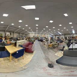 Ruim interieur van kringloopwinkel met verschillende zithoeken, meubels en artikelen uitgestald onder LED-verlichting