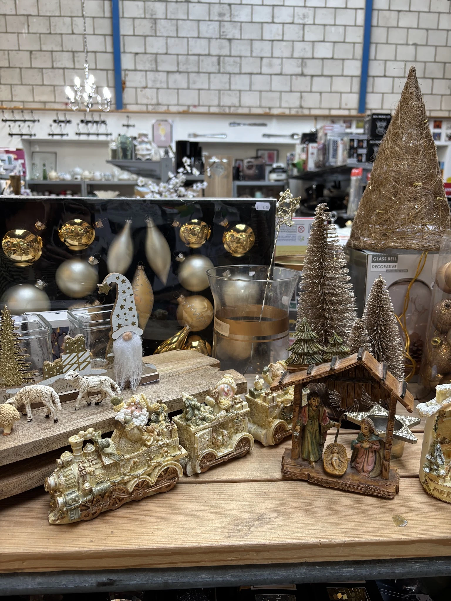 Uitgestalde kerstdecoratie met gouden en zilveren ballen, kerstbomen, kaarshouders en kerstfiguren op houten display