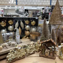 Uitgestalde kerstdecoratie met gouden en zilveren ballen, kerstbomen, kaarshouders en kerstfiguren op houten display