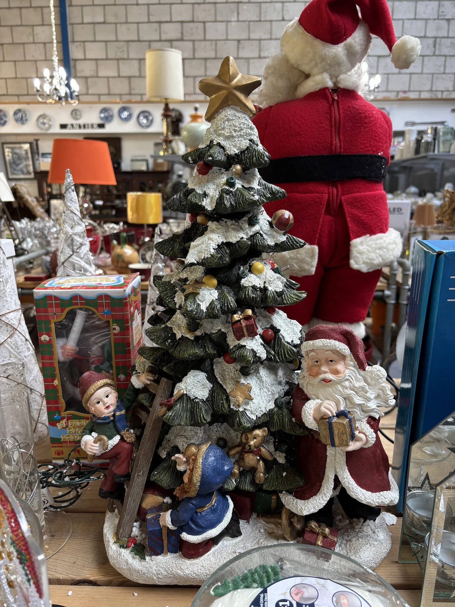 Uitgestalde kerstdecoratie met kerstbomen, kerstman-figuren en rode kerstsokken in de winkel