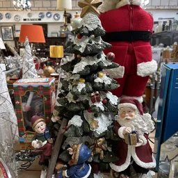 Uitgestalde kerstdecoratie met kerstbomen, kerstman-figuren en rode kerstsokken in de winkel