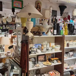 Stellingen vol huishoudelijke artikelen, servies, lampen en decoratieve voorwerpen in een kringloopwinkel