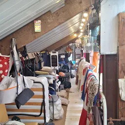 Zolder of opslagruimte vol met kleding, tassen en huishoudartikelen aan rekken en haakjes