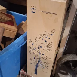 Close-up van een decoratief houten paneel met geblokt patroon en blauwe bloemmotief.