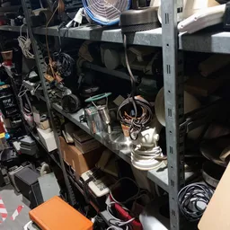 Metalen stellingkast met diverse elektrische apparaten en onderdelen zoals lampen en kabels