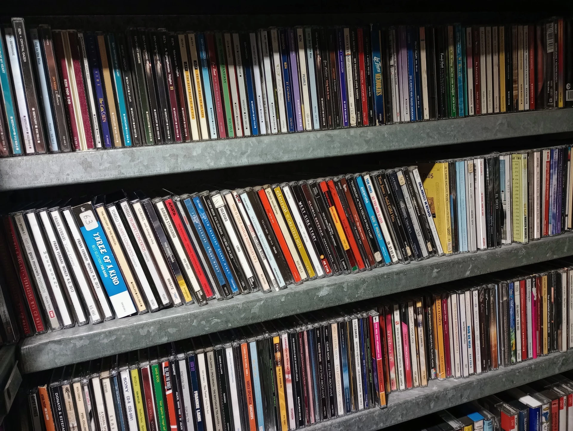 Drie volle stellingen met honderden cd's en dvd's netjes op rij geordend