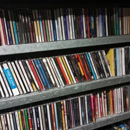 Drie volle stellingen met honderden cd's en dvd's netjes op rij geordend