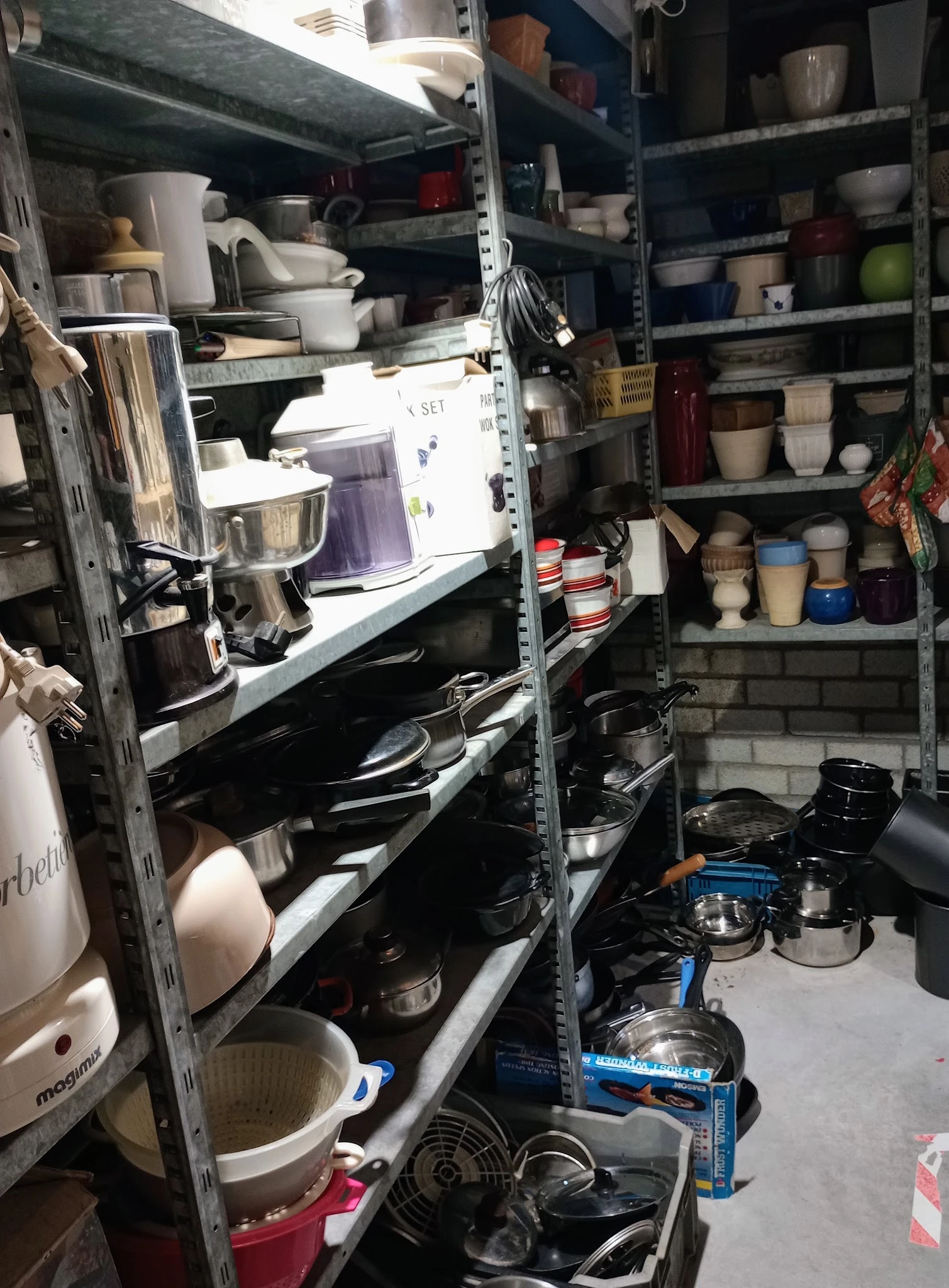 Stellingen met keukengerei, serviesgoed en huishoudartikelen in een kringloopwinkel