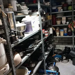 Stellingen met keukengerei, serviesgoed en huishoudartikelen in een kringloopwinkel