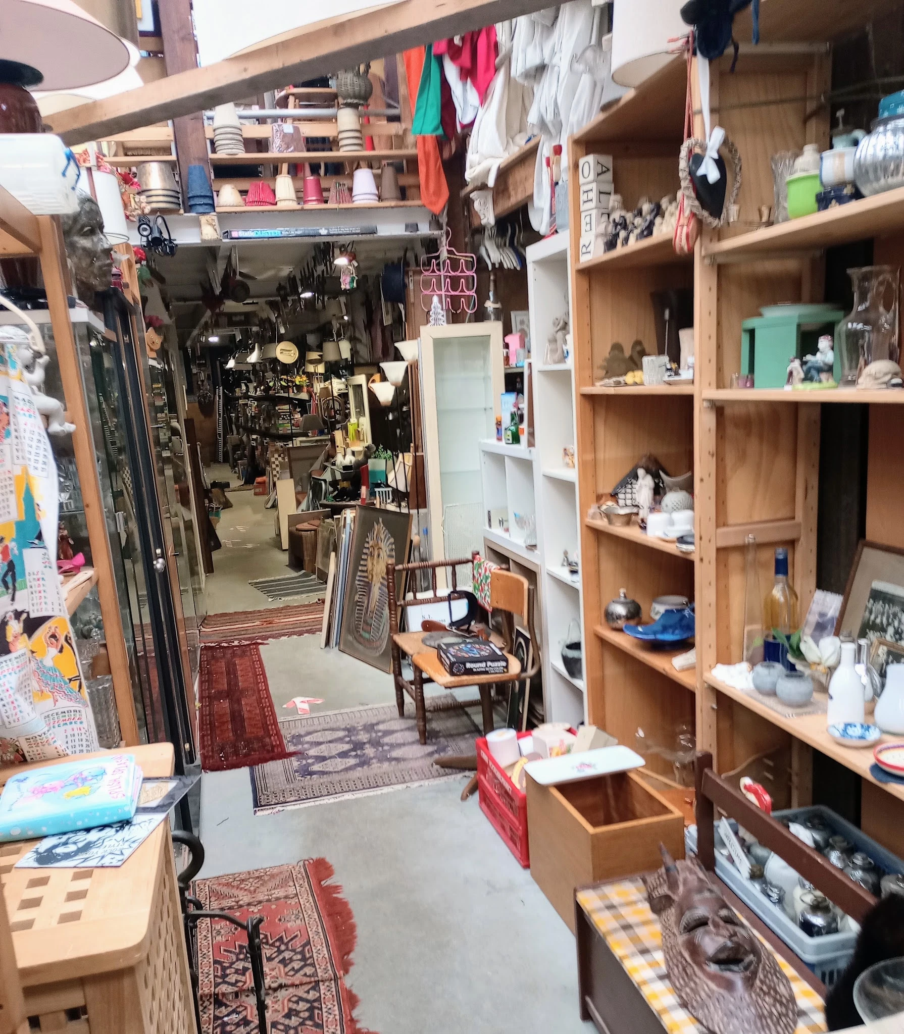 Winkelvloer met houten stellingen, winkelrekken en diverse tweedehands spullen in de kringloopwinkel