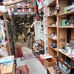 Winkelvloer met houten stellingen, winkelrekken en diverse tweedehands spullen in de kringloopwinkel