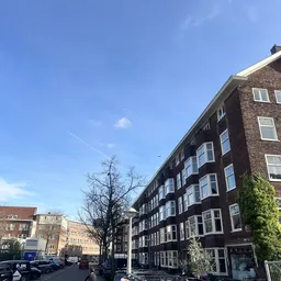 Straatgezicht met meerlagige bakstenen woningbouwgebouwen onder blauwe hemel