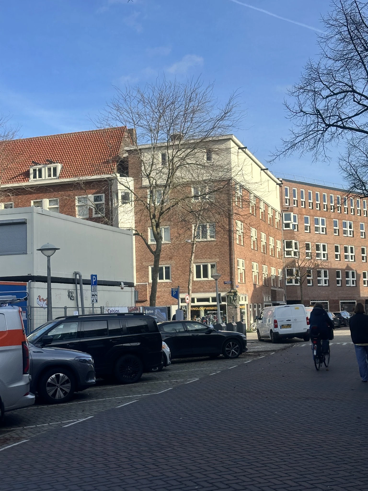 Straatgezicht met voorkant van bakstenen gebouwen, geparkeerde auto's en fietsers