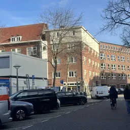 Straatgezicht met voorkant van bakstenen gebouwen, geparkeerde auto's en fietsers