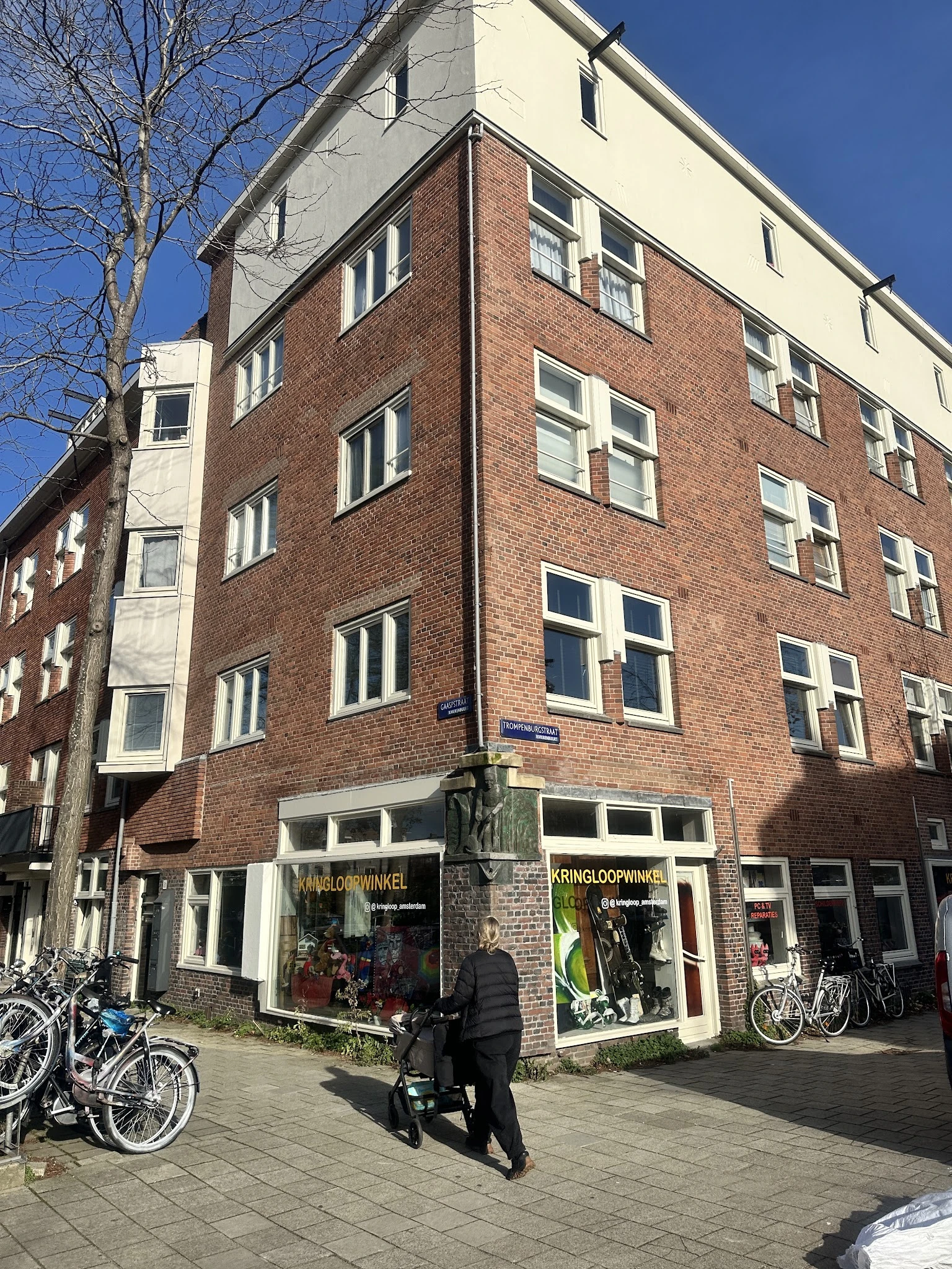 Bakstenen gevel van een kringloopwinkel met etalages op de begane grond en ramen op de bovenverdiepingen