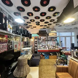 Winkelbinnenruimte met plafondversiering van vinyl records, displays met boeken en media, en diverse tweedehandsartikelen
