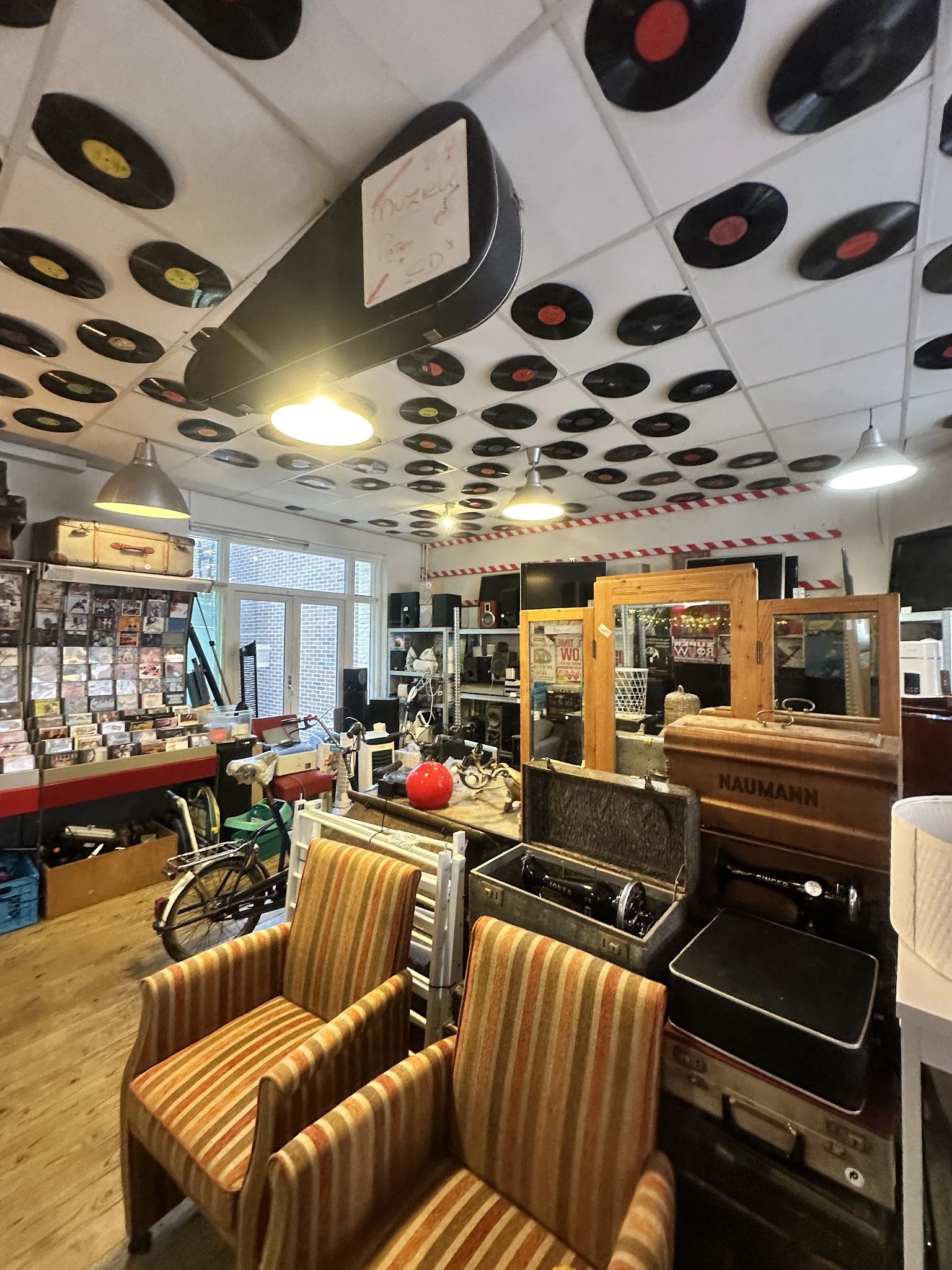 Winkelvloer van kringloopwinkel met meubels, rekken en vintage artikelen onder plafond met vinyl records