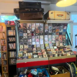 Uitgestalde cd's en dvd's in glazen vitrine met houten kisten erboven in kringloopwinkel