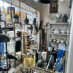 Stellingen en tafels met diverse huishoudelijke artikelen zoals servies, glazen, kandelaars en decoratieve voorwerpen