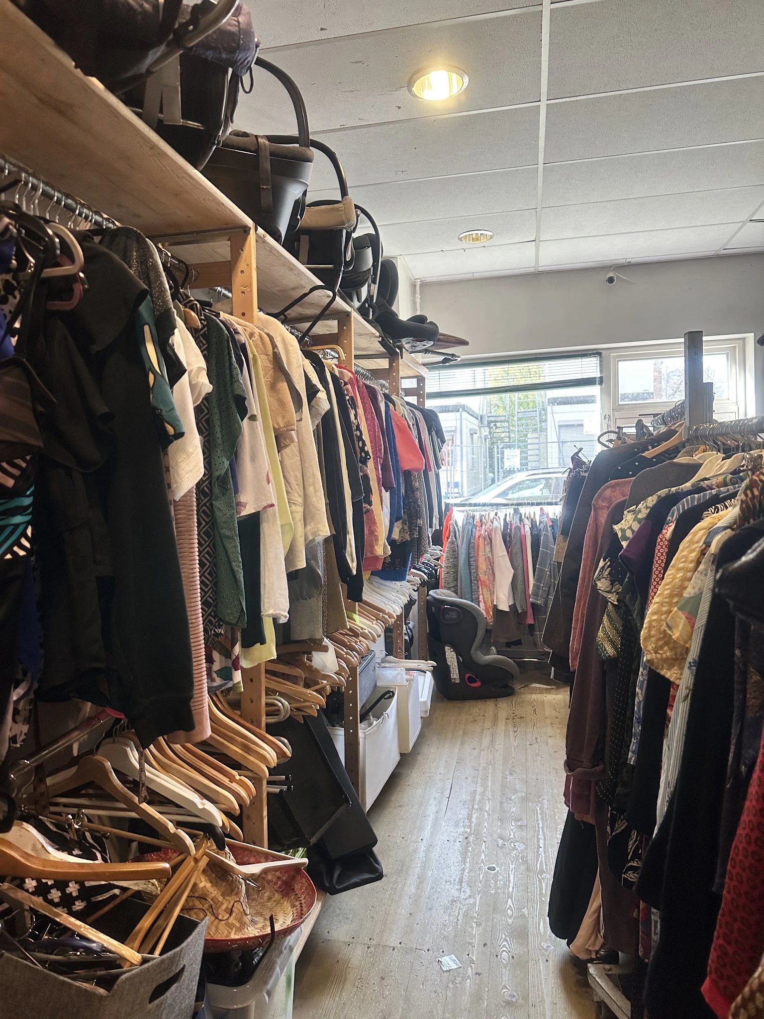 Rekken met tweedehands kleding in diverse kleuren en stijlen in de winkel