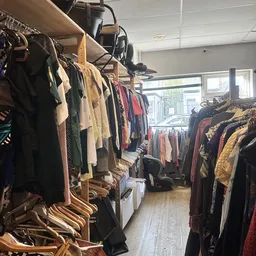 Rekken met tweedehands kleding in diverse kleuren en stijlen in de winkel