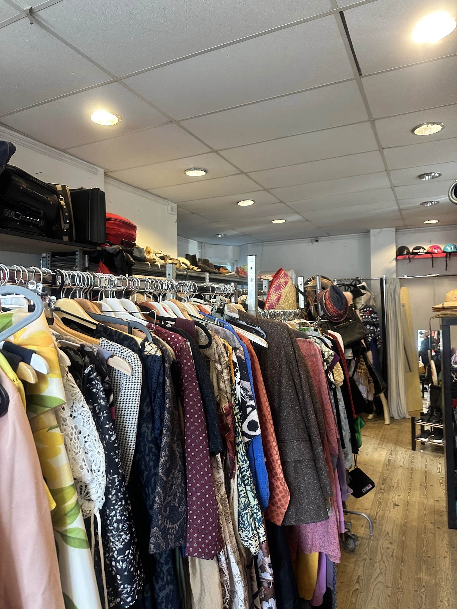 Rekken met tweedehands kleding, waaronder jassen, truien en broeken in verschillende kleuren en stijlen