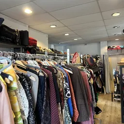 Rekken met tweedehands kleding, waaronder jassen, truien en broeken in verschillende kleuren en stijlen