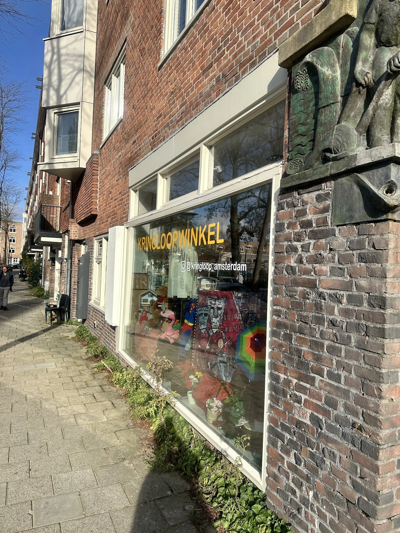 Winkelgevel met gele letters 'KRINGLOOP WINKEL' op raam, uitstallingen met spullen zichtbaar, bakstenen gevelbekleding