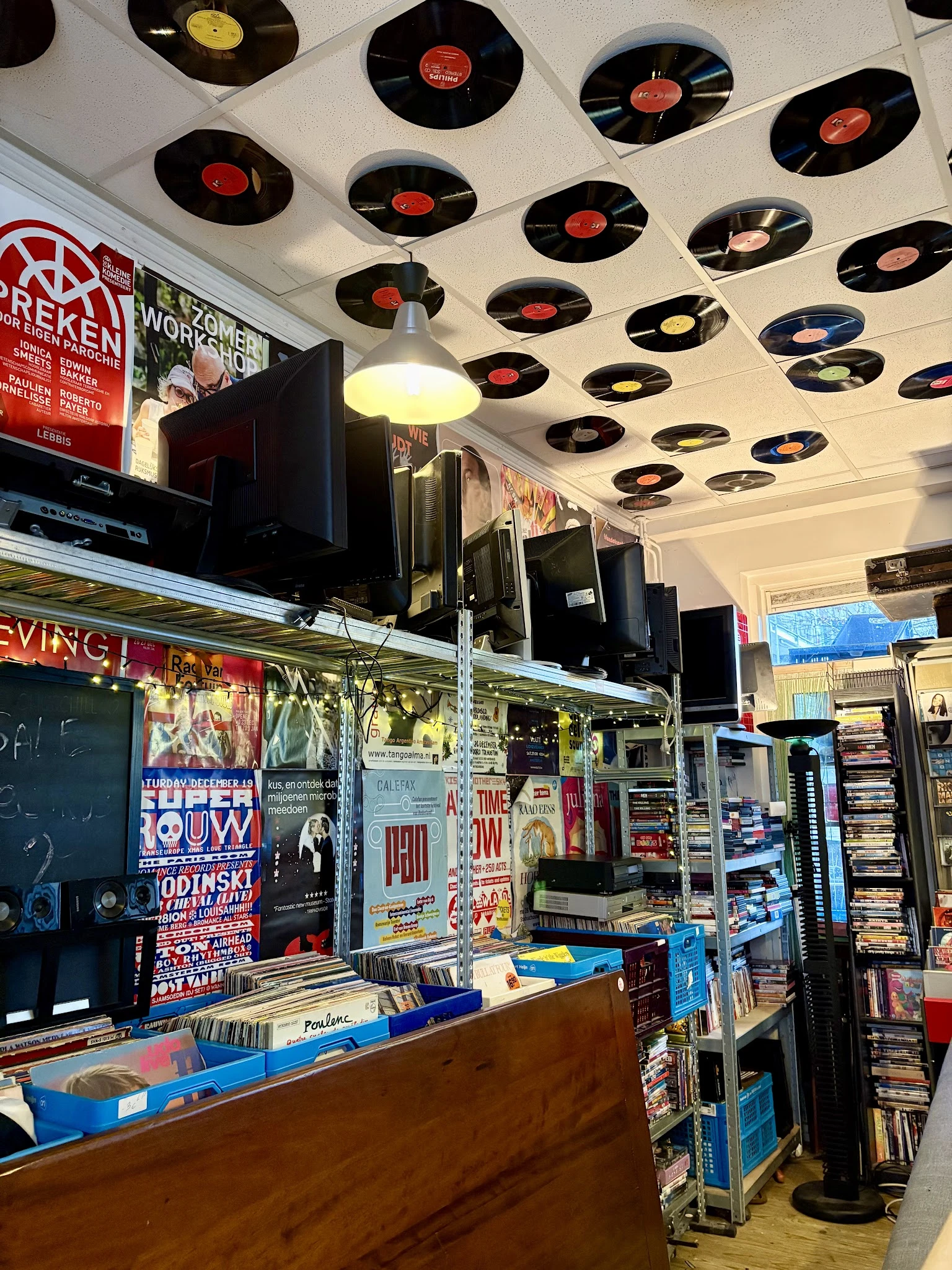Winkelinterieur met plafond versierd met vinyl records, stellingen met merchandise en posters aan de muur