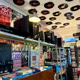 Winkelinterieur met plafond versierd met vinyl records, stellingen met merchandise en posters aan de muur