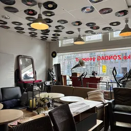 Interieur van kringloopwinkel met meubels, spiegels, lampen aan plafond en uitzicht op straat