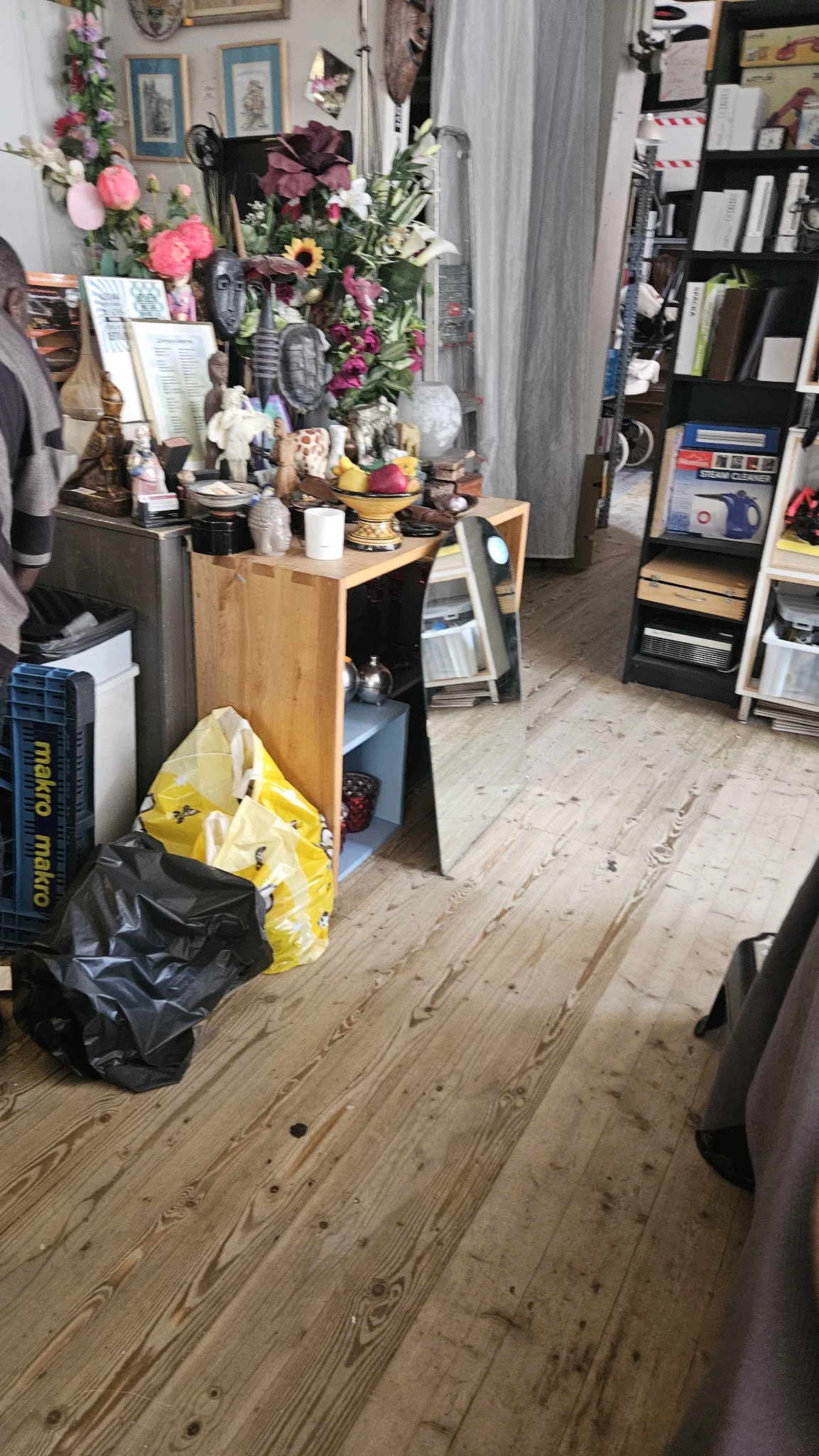 Winkelvloer met houten planken, stellingen, dozen en diverse spullen in een kringloopwinkel