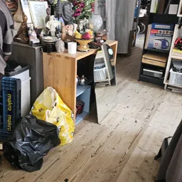 Winkelvloer met houten planken, stellingen, dozen en diverse spullen in een kringloopwinkel