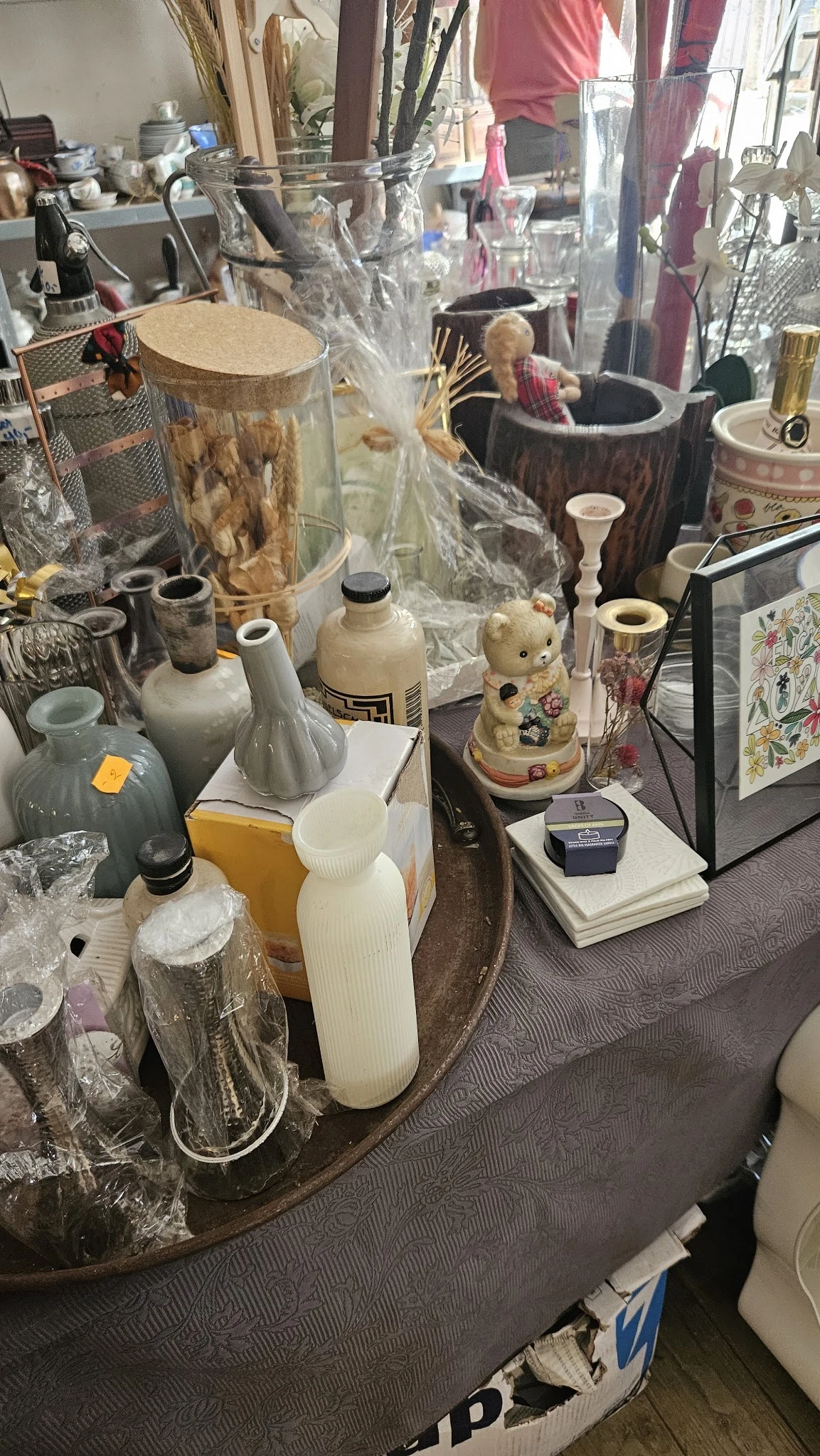 Uitgestalde tweedehands huishoudartikelen en decoratiestukken waaronder vazen, kandelaars en keramische items op toonbanken