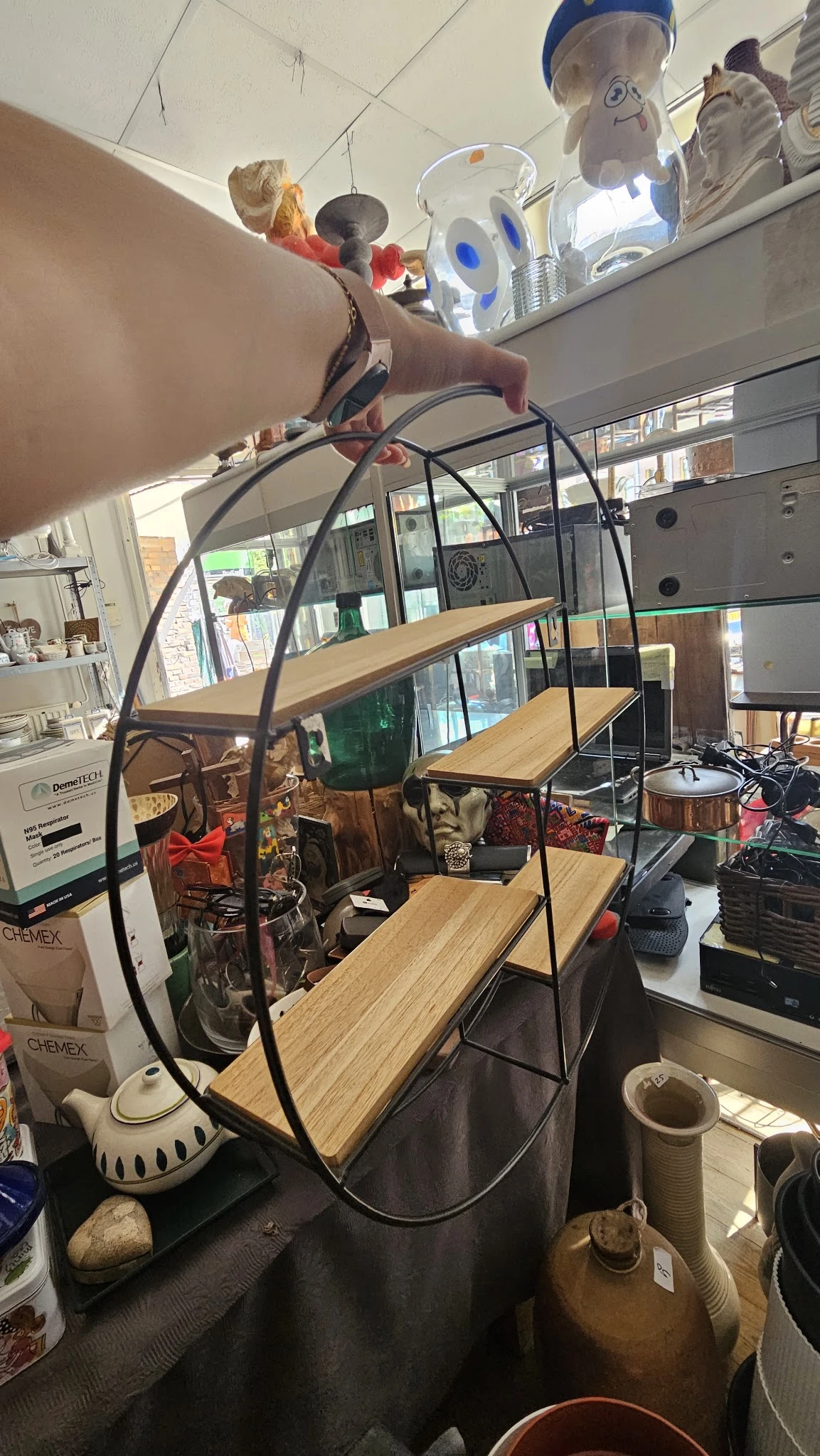 Winkelinterieur met houten tafels, zwart metalen stellingkast en diverse spullen op display
