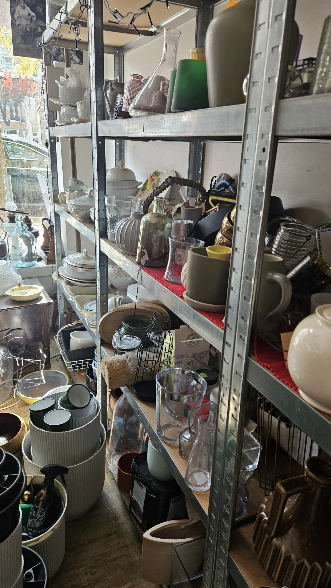 Glazen vitrinekasten met servies, kopjes, kannen en huishoudartikelen in verschillende vakken