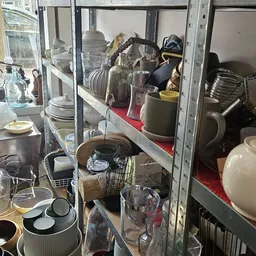 Glazen vitrinekasten met servies, kopjes, kannen en huishoudartikelen in verschillende vakken