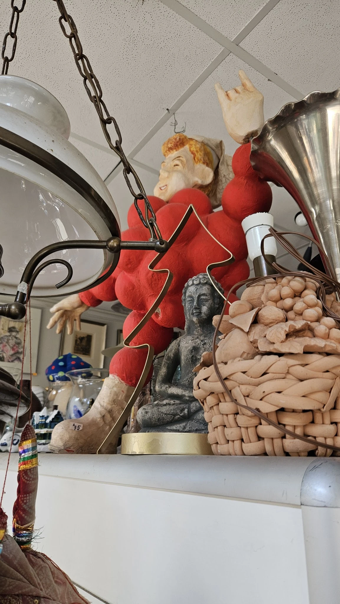 Diverse decoratieve items: rode kerstversiering, grijs beeldhouwwerk, houten kralen en andere tweedehands spullen