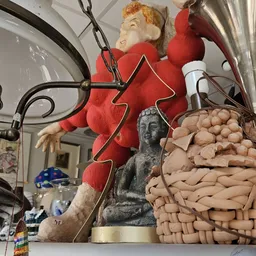 Diverse decoratieve items: rode kerstversiering, grijs beeldhouwwerk, houten kralen en andere tweedehands spullen