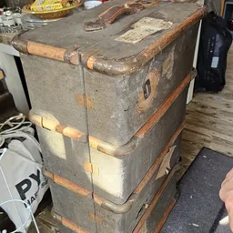 Oude vintage koffer of reiskoffer met leerlabels en koperen hoeken, gestapeld op houten onderstel