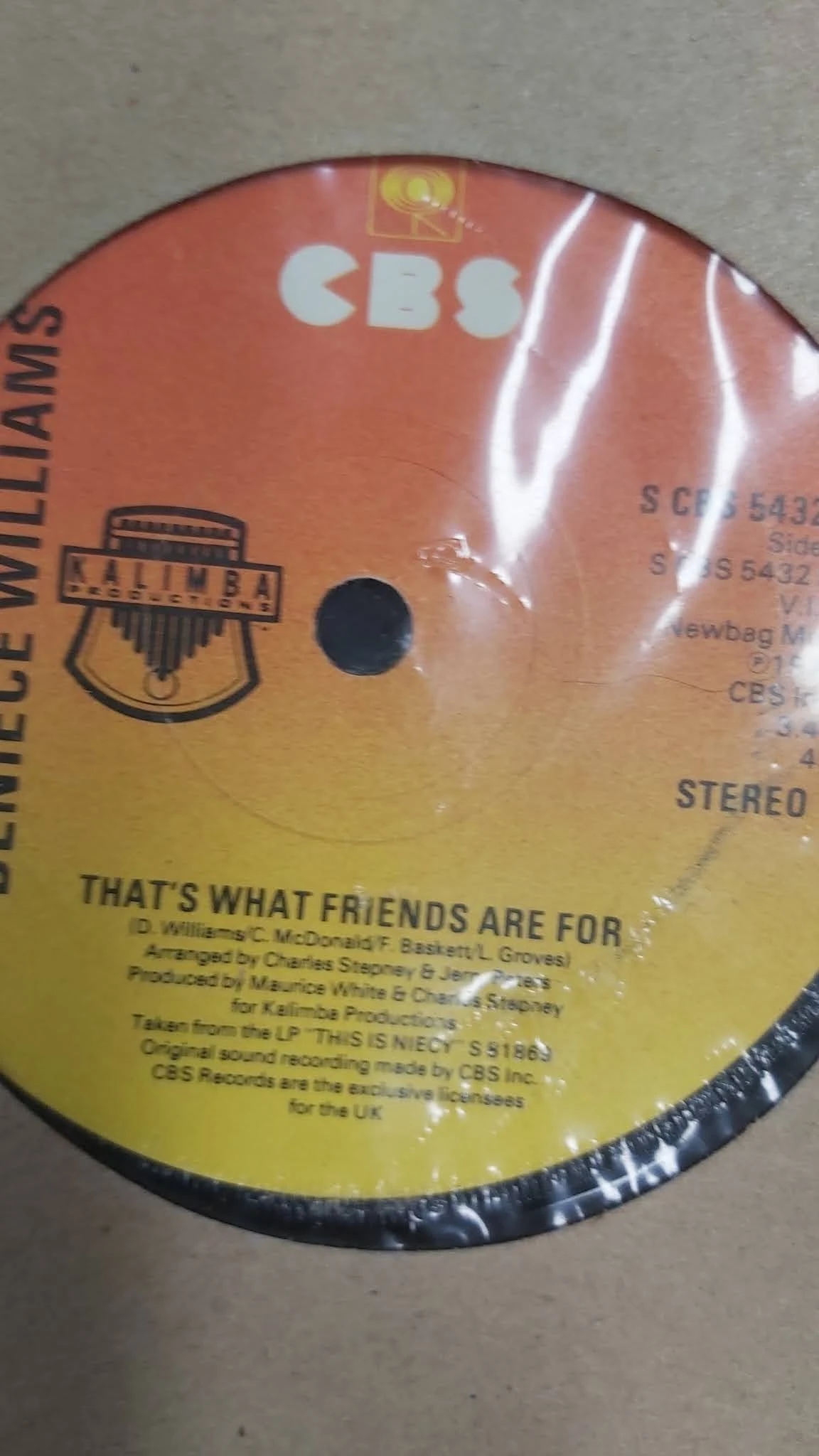Close-up van een vinyl LP-hoes met gele en oranje kleurverloop, gedeeltelijk in plastic verpakt