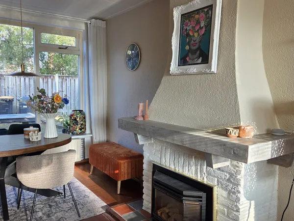 Woonkamerinterieur met open haard, zithoek en uitzicht op terras met decoratieve accessoires