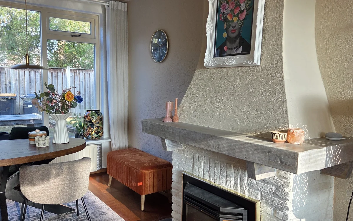 Woonkamerinterieur met open haard, zithoek en uitzicht op terras met decoratieve accessoires