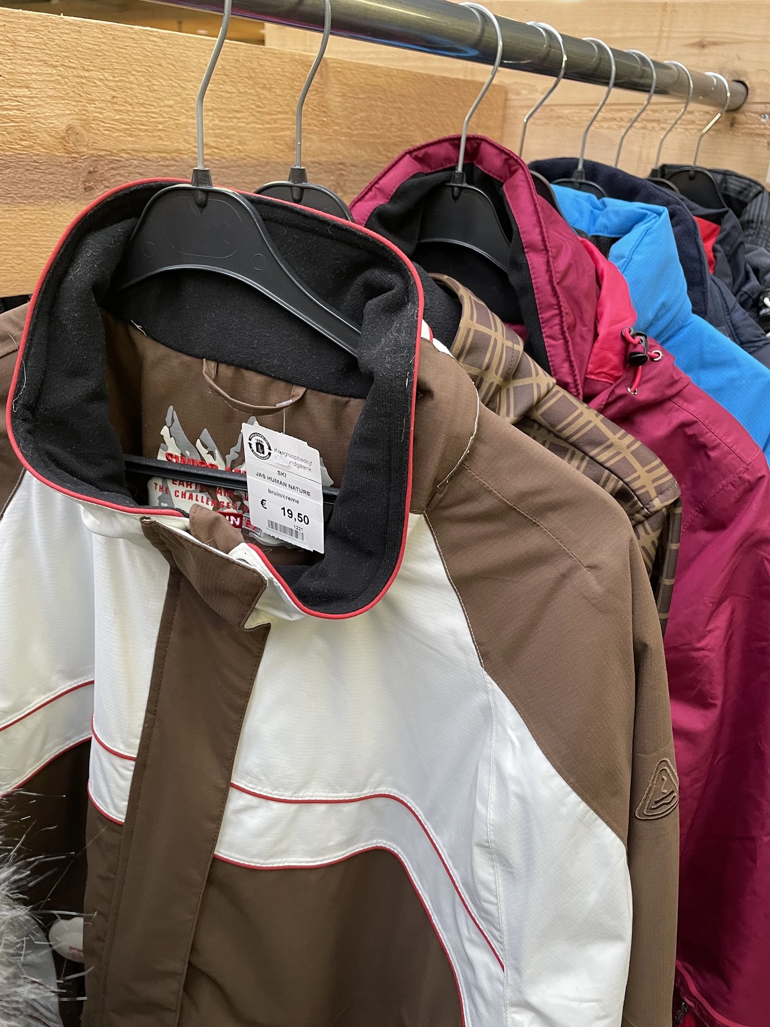 Uitgestalde tweedehands jassen en jasjes in verschillende kleuren met prijskaartje van 19,50 euro