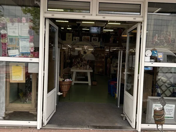 Entreepui van kringloopwinkel met openstaande deuren en uitzicht op winkelinterieur