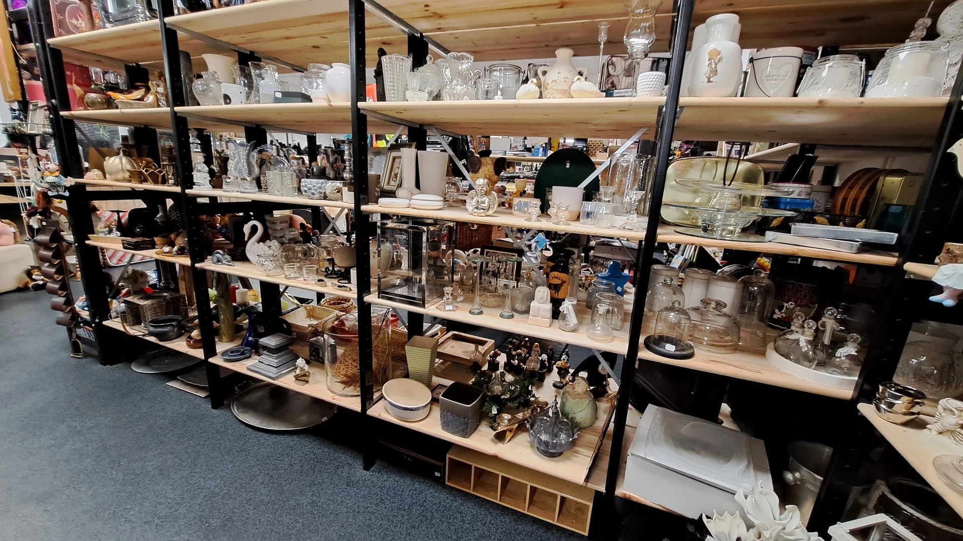 Stellingen vol met huishoudelijke artikelen, glaswerk, servies en decoratieve items